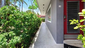 A corridor with a red door marked '10', surrounded by lush greenery and palm trees.