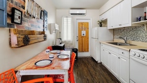 A compact kitchen with white cabinets, a wooden table, and a brick wall.