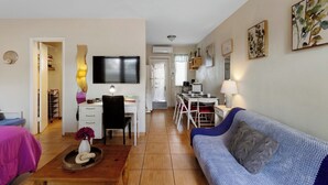 Una sala de estar acogedora con un sofá, una mesa de centro, un televisor y un comedor con sillas y una mesa.