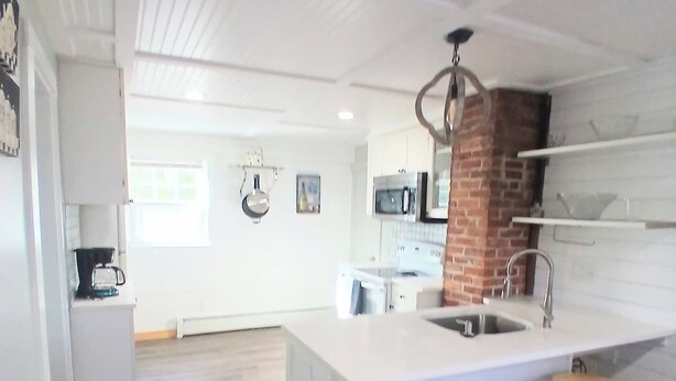 A modern kitchen with a large island, bar stools, and a brick accent wall.