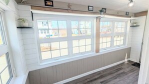 A room with large windows, wooden paneling, and a ceiling fan.