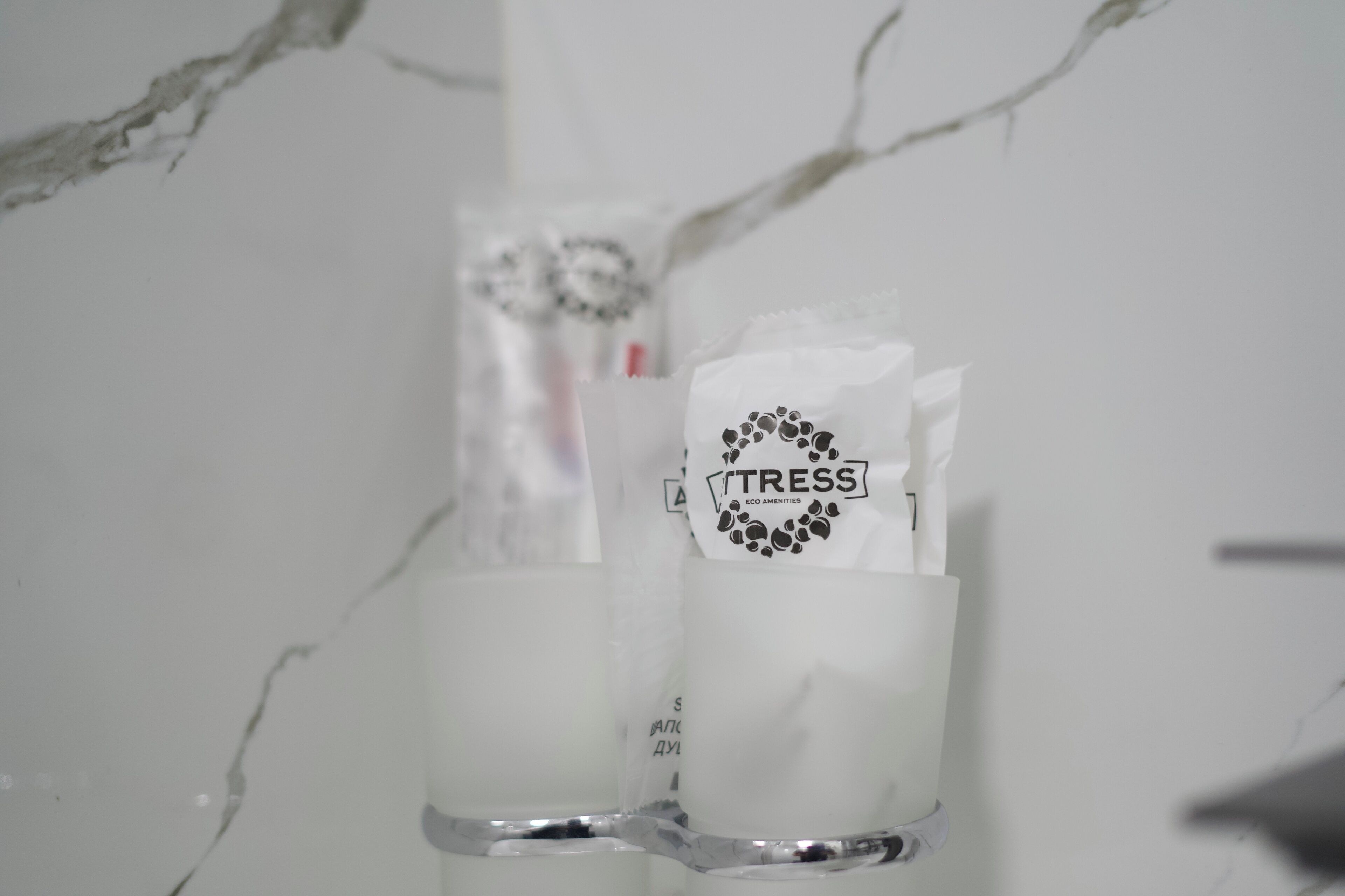 Une salle de bain avec un mur en marbre, un distributeur de serviettes et un flacon de savon pour les mains.