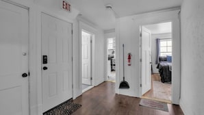 A hallway with white doors, a fire extinguisher, a broom, and a welcome mat. - Cozy 3BR Near UB & Niagara Falls - Pet Friendly (Buffalo)