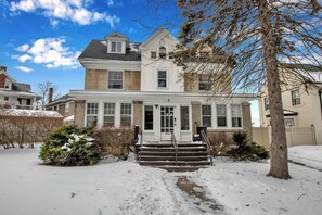 A two-story house with a front porch, a chimney, and a snow-covered yard. - Cozy 3BR Near UB & Niagara Falls - Pet Friendly (Buffalo)