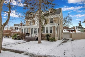 A two-story house with a front porch, a garage, and a snow-covered driveway. - Cozy 3BR Near UB & Niagara Falls - Pet Friendly (Buffalo)