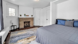 A bedroom with a bed, a fireplace, a nightstand, and a window. - Cozy 3BR Near UB & Niagara Falls - Pet Friendly (Buffalo)