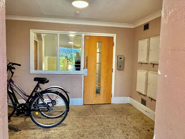 A hallway with a wooden door, a window, and a bicycle parked against the wall.