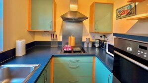 Una cocina moderna con armarios verde azulado, una campana extractora de acero inoxidable y un horno empotrado.
