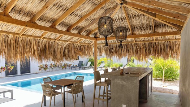 A poolside area with a thatched roof, a bar, and lounge chairs. - Villa Valena 4 Centrally located, beach, restaurant and promenade within walking distance (Kralendijk)
