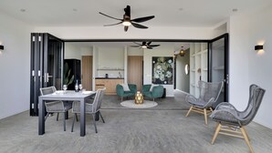 A modern interior with a dining area, two green armchairs, a round table, and a ceiling fan. - Villa Valena 4 Centrally located, beach, restaurant and promenade within walking distance (Kralendijk)