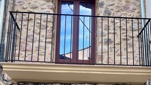 Un bâtiment en pierre avec une porte en bois et un balcon. Une enseigne au-dessus de la porte indique : « Casa Raquel ».