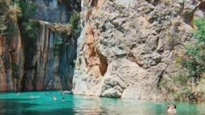 Une piscine d’eau cristalline, entourée de falaises rocheuses.