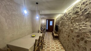 Un coin repas avec un sol à carreaux, une table entourée de chaises et un mur en pierre.