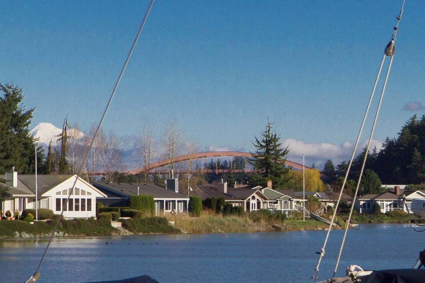 Vista de un lago con casas y un puente al fondo.