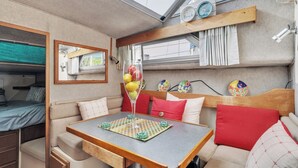 A compact RV interior with a dining area, a bed, and a small kitchenette. - Luxury Yacht 2 BR Marina Views & Wifi (Anacortes)