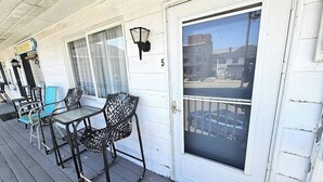 Une véranda avec des meubles d’extérieur, une porte avec un numéro et une vue sur la rue.