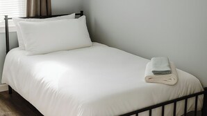 A neatly made bed with white linens and a folded towel on the side. - Cozy 2BR Home: With Lake Access & Work Space (Mercer)