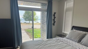 Un dormitorio con cama, vistas al exterior y una ventana con persianas.