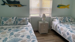 A bedroom with two beds, a window with blinds, a ceiling fan, and wall decorations of fish. - Charming 2-bedroom townhome with bay front views in delightful Ocean City (Ocean City)