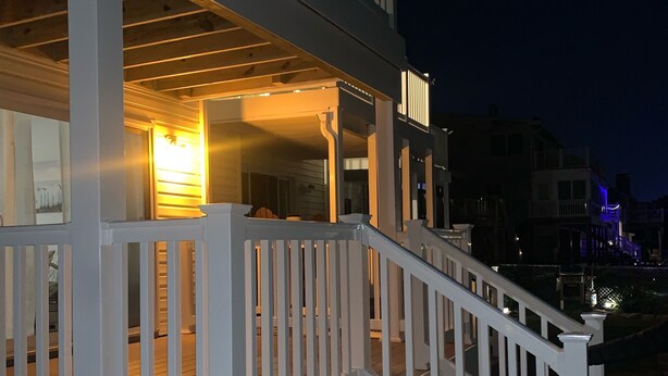 A two-story building with a white exterior, a balcony on the upper floor, and a staircase leading to the entrance. - Charming 2-bedroom townhome with bay front views in delightful Ocean City (Ocean City)