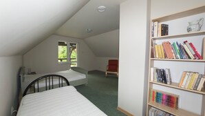 A room with a bunk bed, a bookshelf, and a window.