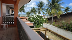 Enjoy the ocean view from this balcony with a tiled floor and wooden railing, perfect for taking in the sights of palm trees and lush surroundings.
