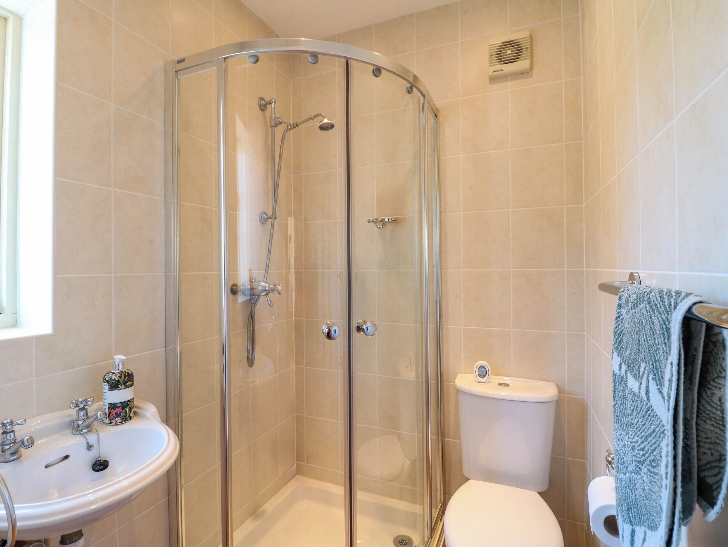 Een badkamer met een douchecabine, een wastafel, een toilet en een handdoekhouder.