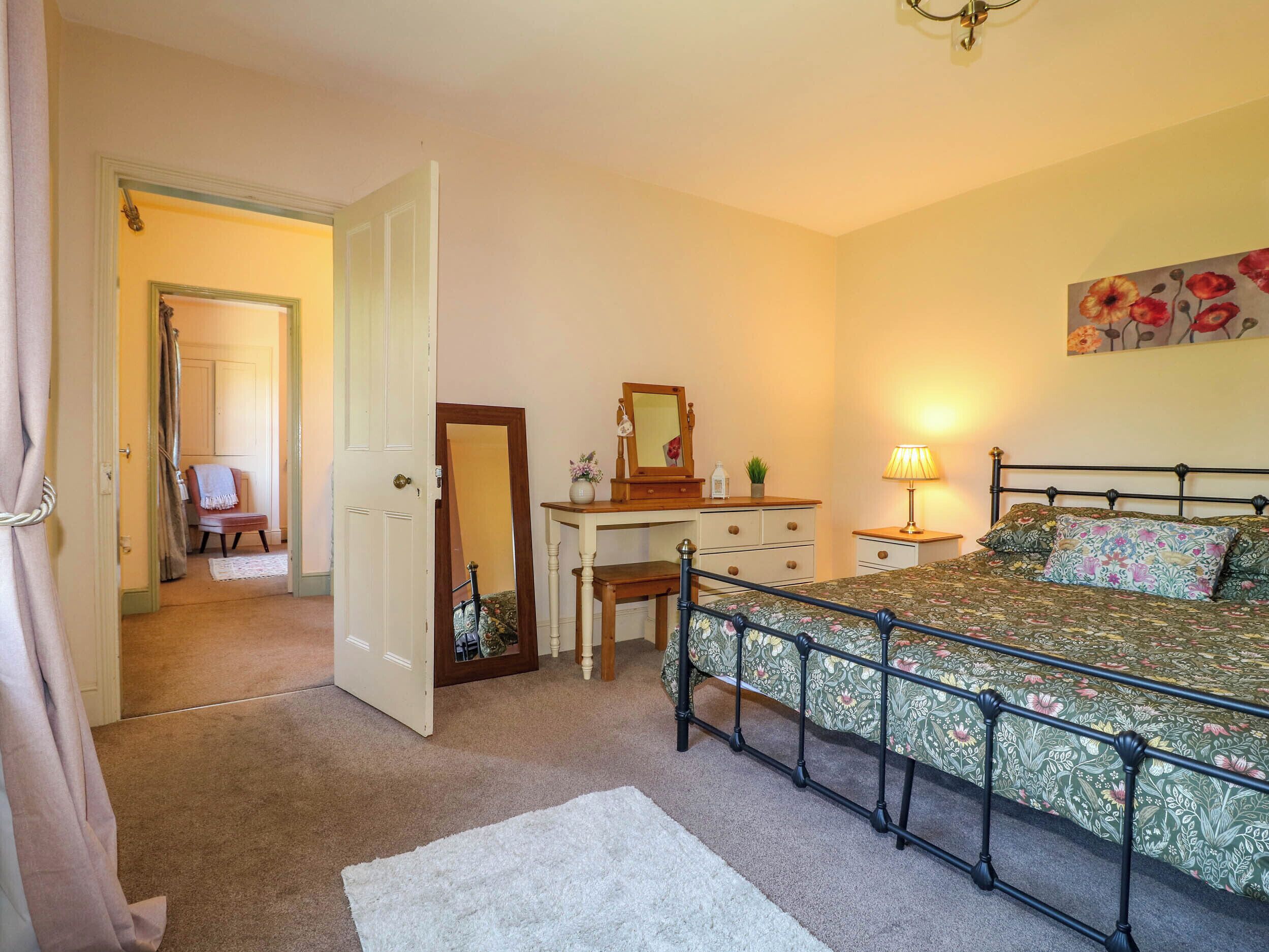 A bedroom with a bed, a dresser, a chair, a desk, and a mirror.