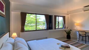 Ein Hotelzimmer mit zwei Betten, einem Schreibtisch, einem Stuhl und einem Fenster mit Vorhängen.