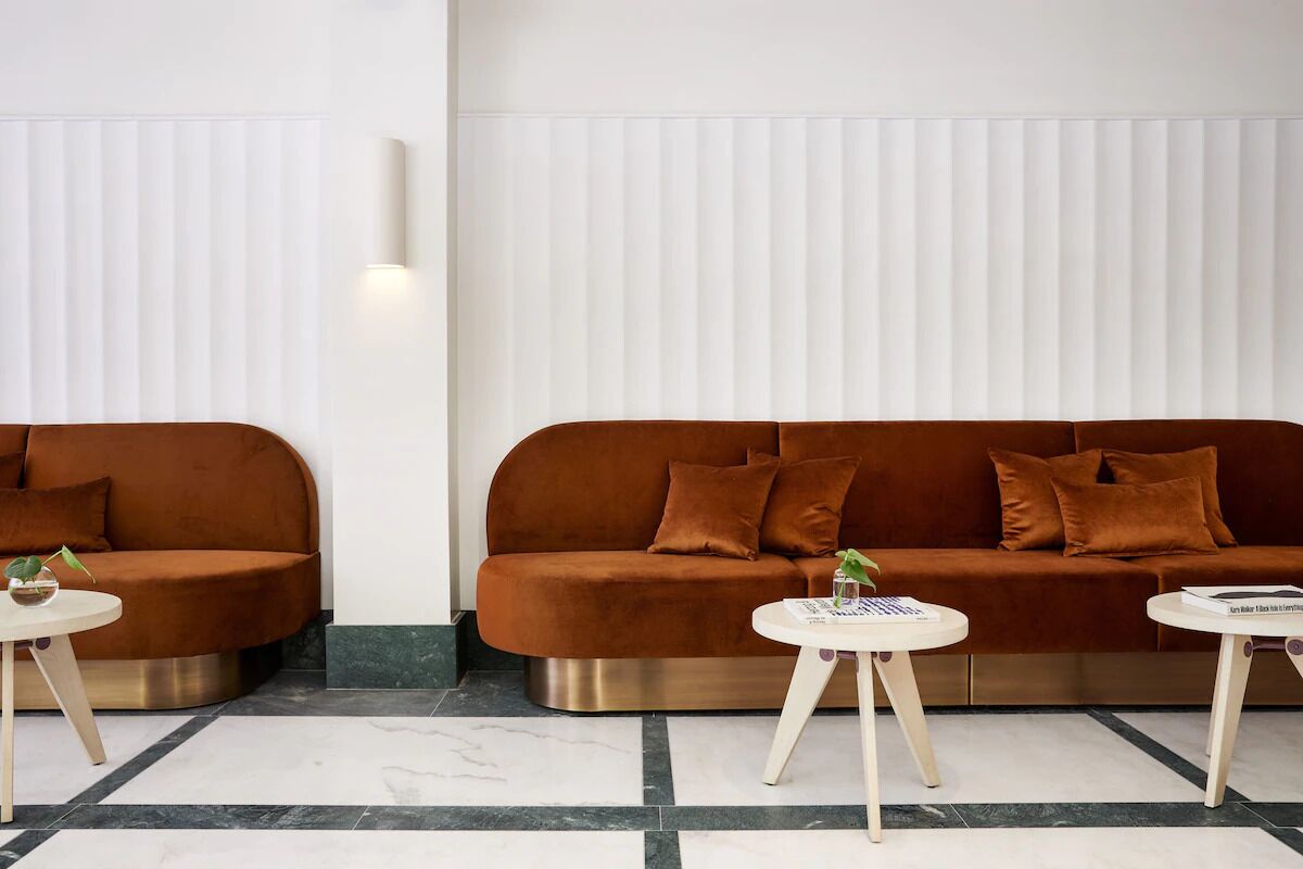 Una sala de estar moderna con dos sofás, una mesa de centro y una lámpara fijada en la pared.