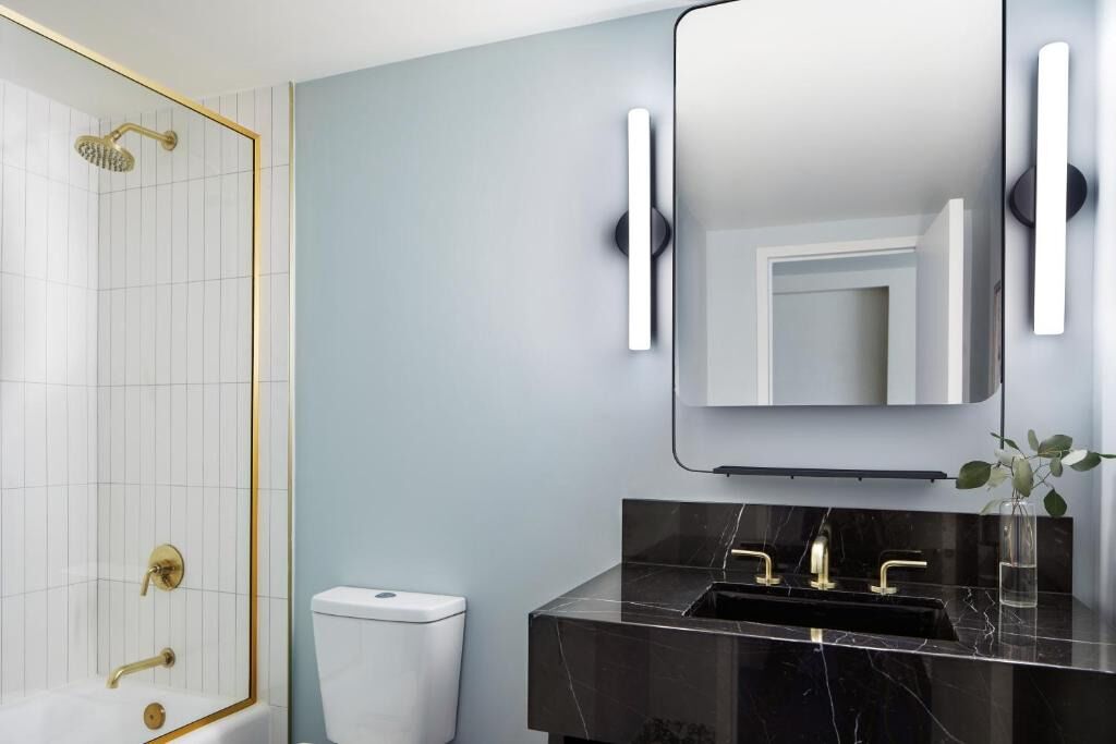 Une salle de bain moderne avec un lavabo en marbre, des robinetteries dorées et un grand miroir.