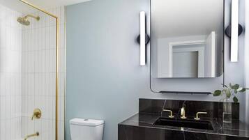 Une salle de bain moderne avec un lavabo en marbre, des robinetteries dorées et un grand miroir.