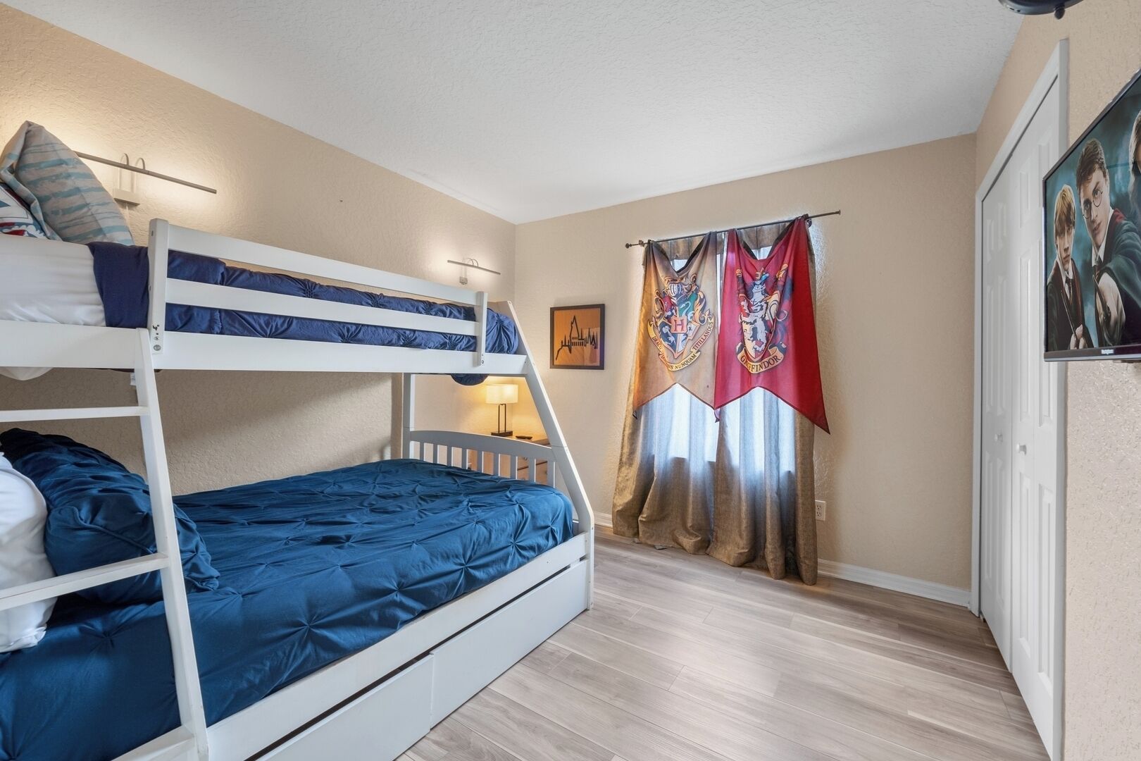 A bunk bed room with a lamp, curtains, and a poster on the wall.