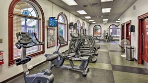 Ein Fitnessstudio mit mehreren Laufbändern, Fahrrädern und einer Spiegelwand.