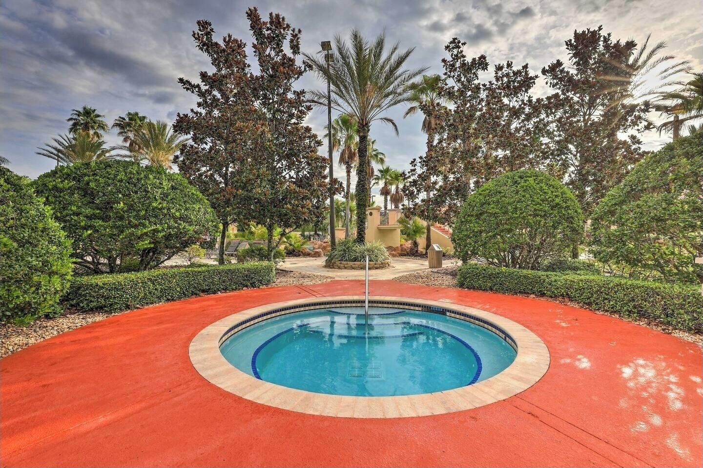 A swimming pool with a red deck, surrounded by various trees and shrubs.