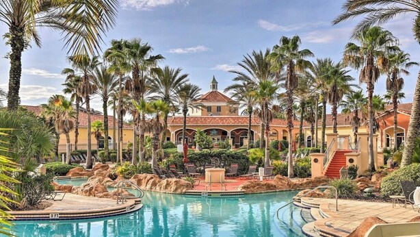 Ein Resort mit einem zentral gelegenen Pool, Palmen und einem Gebäude mit rotem Ziegeldach.
