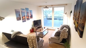 A living room with a sofa, a coffee table, a TV, and artwork on the wall.