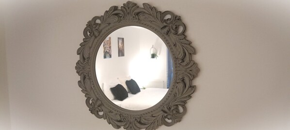 A round mirror with an ornate frame on a wall.