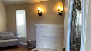 A living room with a fireplace, a sofa, a patterned rug, and wall-mounted lights.