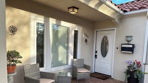 A covered patio with wicker furniture, a door, and a mailbox.