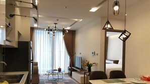 Una habitación de hotel moderna con cocina, comedor y un gran ventanal con cortinas.