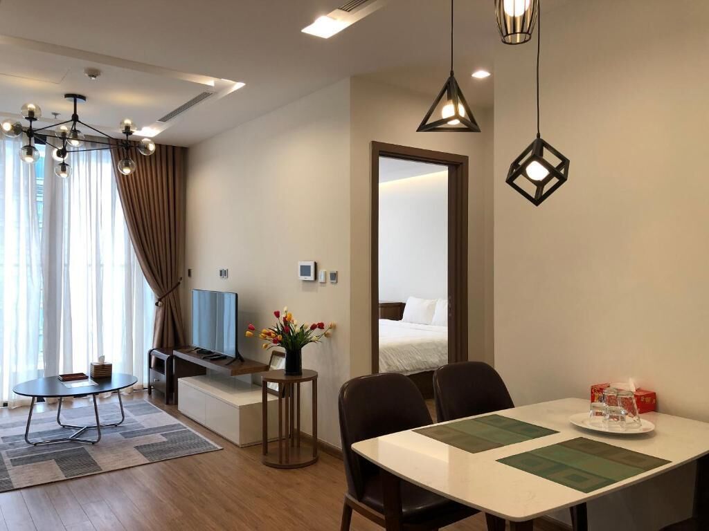 Een hotelkamer met een eethoek, een televisie, een bed en een grote spiegel.
