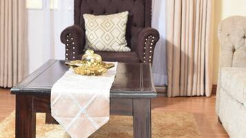 Una mesa de centro de madera oscura con un mantel blanco y un cuenco decorativo, sobre una alfombra suave color beige.