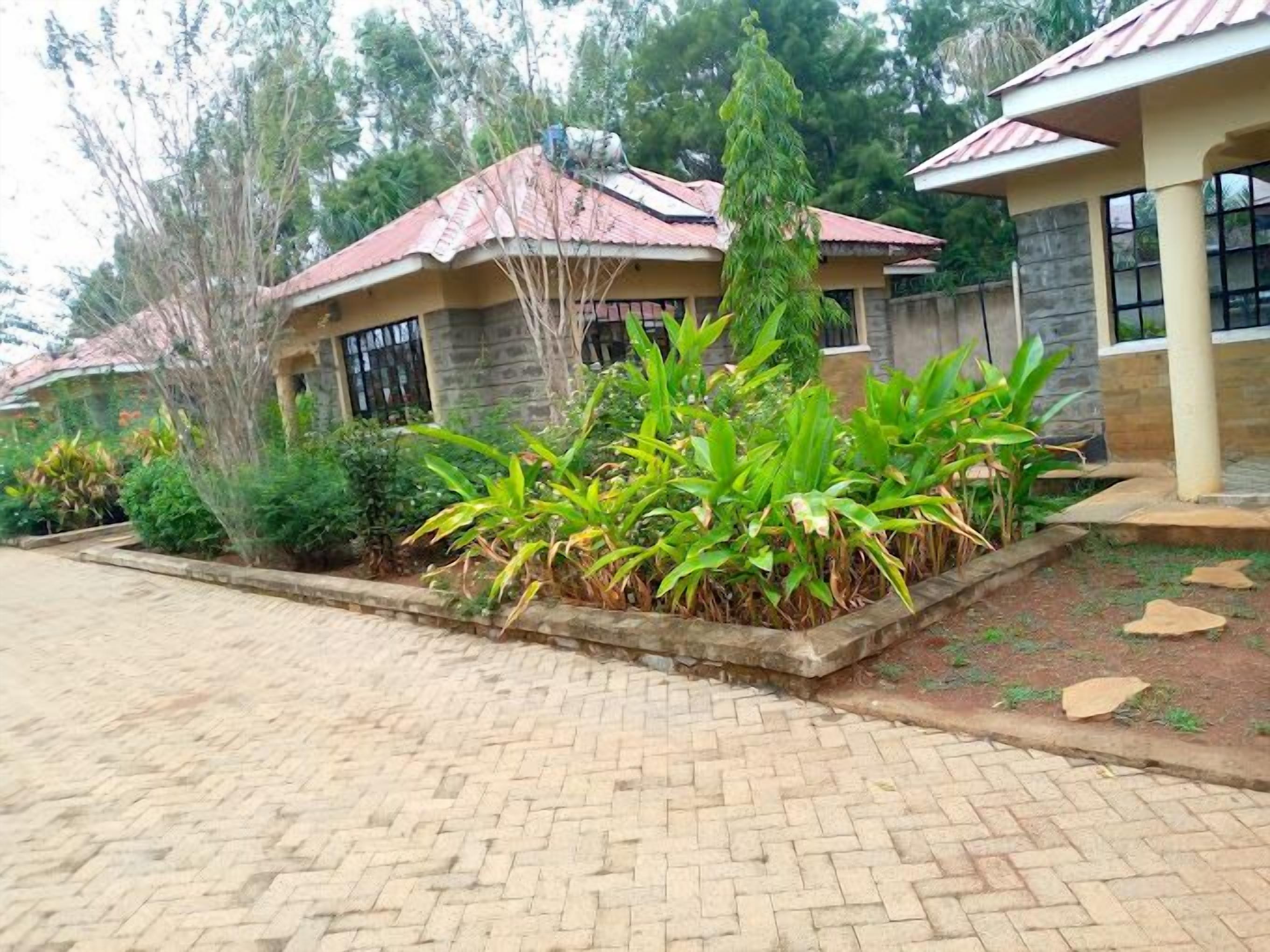 Una casa con entrada de ladrillo y un jardín con diversas plantas.