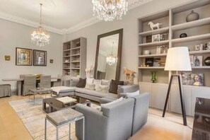 Una sala de estar moderna con un sofá modular, una mesa de centro, una araña y una estantería.