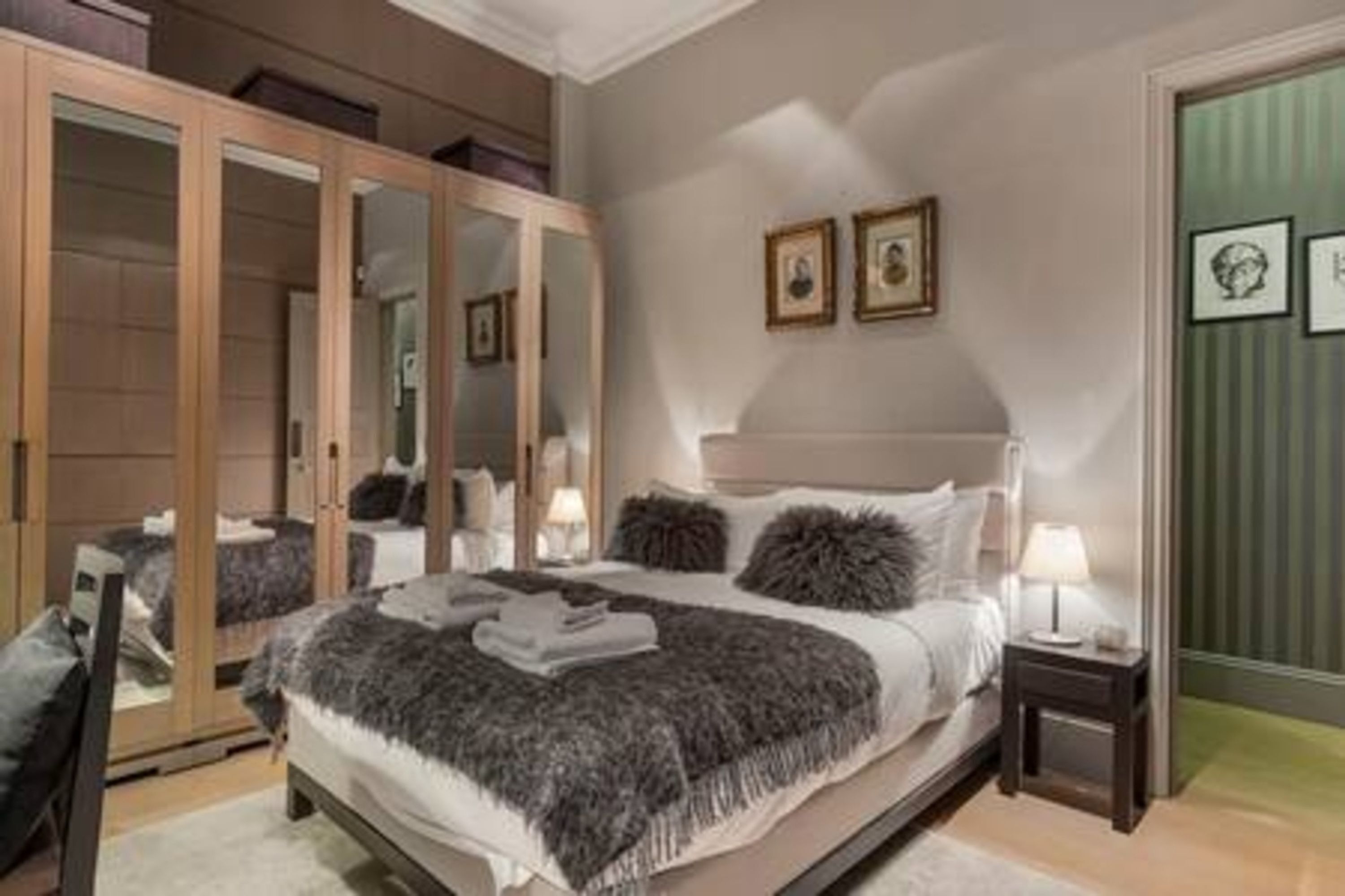 A bedroom with a large bed, a wardrobe, and a bedside table with a lamp.
