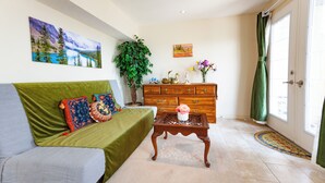 A living room with a green sofa, a wooden coffee table, a dresser, and a large plant. - Cozy tidy private | Sunset Garden (Cochrane)