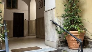 A staircase with stone steps leading to a door, a potted plant on the right, and a wall with a climbing vine. - Antela47 Sleep&Stay Naples (Naples)