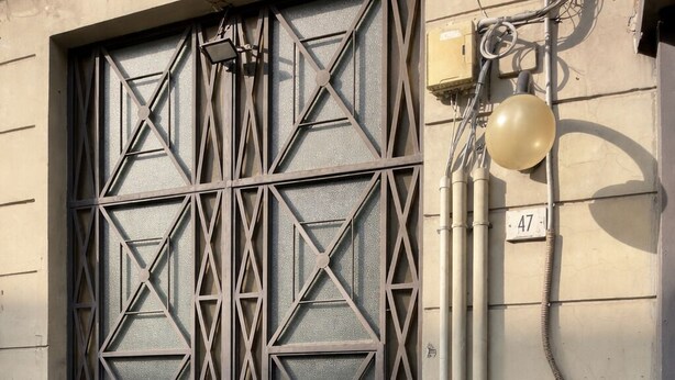 A metal gate with geometric patterns, a potted plant, and a utility pole with cables. - Antela47 Sleep&Stay Naples (Naples)