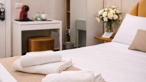 A hotel room with a neatly made bed, a bedside table with a lamp, a small desk with a kettle, and a mirror. - Antela47 Sleep&Stay Naples (Naples)